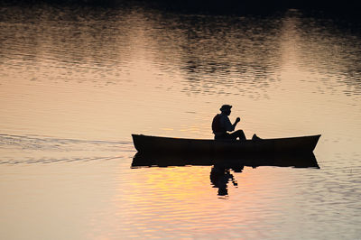 Silhouette person sitting on boat on lake