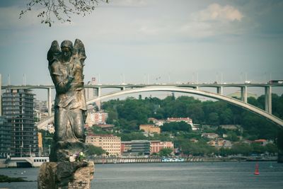 Bridge over river against sky with a angel sculpture 