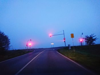 Road sign against clear blue sky at dusk