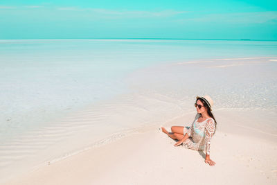Young woman standing at beach against sky