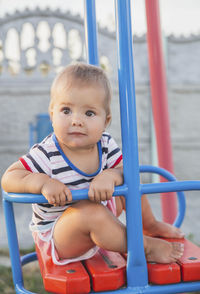 Portrait of boy sitting on slide at playground