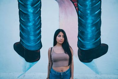 Portrait of young woman standing against wall