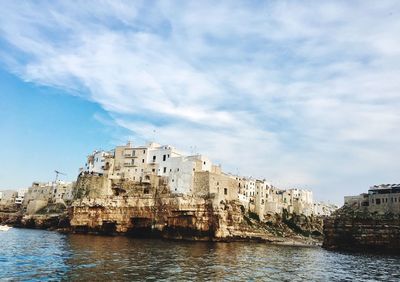 Buildings by sea against sky in city