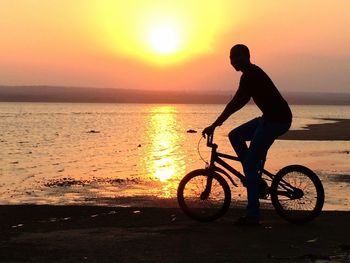 Side view of silhouette man riding bicycle on beach