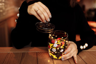 Midsection of woman holding drink on table