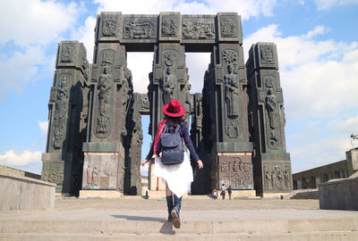 Female impressed by the chronicle of georgia, a gigantic 30 meter tall monument, tbilisi, georgia