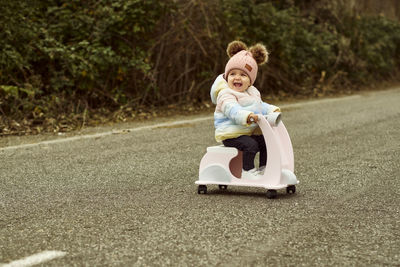 A 1 year old baby girl is with a pink motorcycle outside