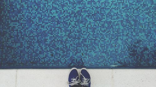 Low section of person standing at poolside