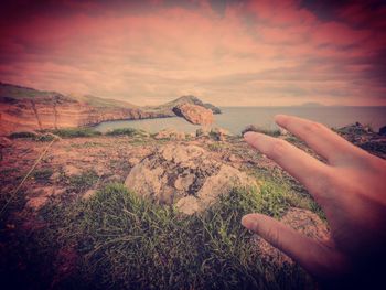 Human hand against sky during sunset