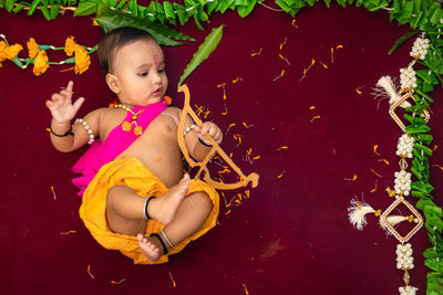 Cute indian boy dresses as lord rama with bow and flowers from top angle