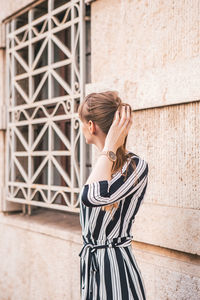 Rear view of woman standing against wall