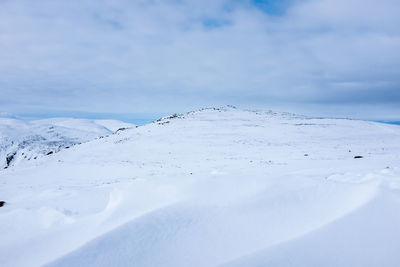 Scenic view of snow covered field against cloudy sky