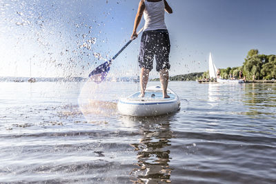 Low section of man paddleboarding on sea