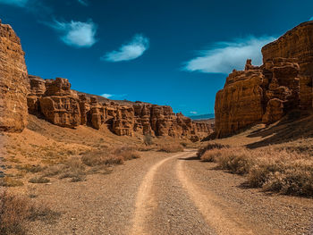 Rock formations on road against sky