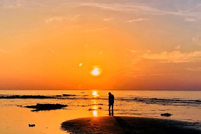 Silhouette people standing on beach during sunset