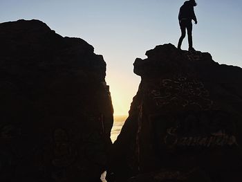 Low angle view of silhouette man on cliff against sky