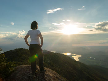 Rear view of man standing on mountain against sky