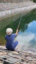 Rear view of man fishing in lake