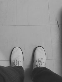 Low section of man standing on tiled floor