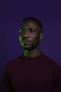 Portrait of young man standing against blue background