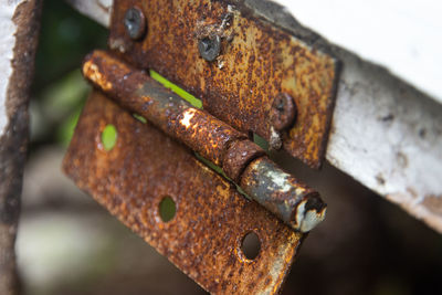 The hinges of a door are rusting and starting to break the metal parts