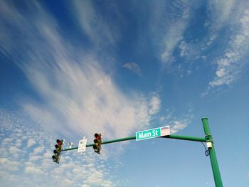 Low angle view of sign board on traffic light pole against blue sky