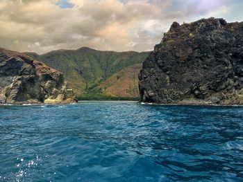 Scenic view of sea by rock formation against sky