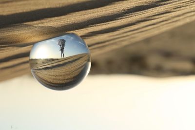 Upside down image of crystal ball on sand