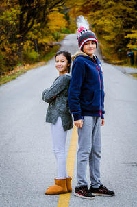 Portrait of smiling siblings standing on road during autumn