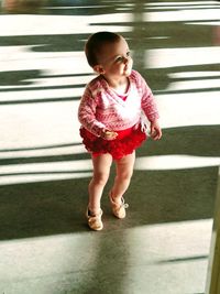 High angle view of cute baby girl looking away while standing on footpath