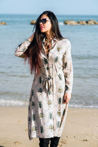 Portrait of young woman standing at beach