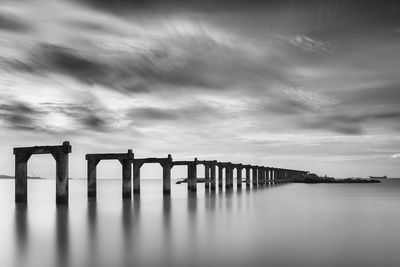 Bridge over sea against cloudy sky