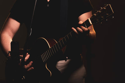 Midsection of man playing guitar