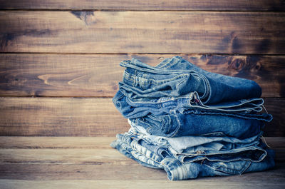 Close-up of stacked folded jeans on hardwood floor at home