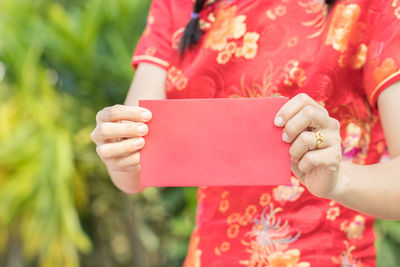 Midsection of woman holding red envelope