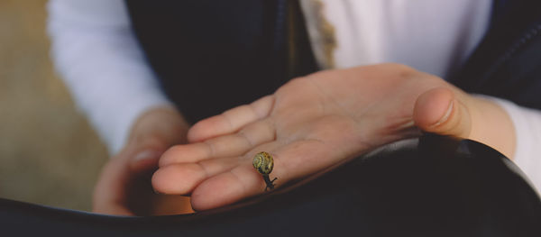 Cropped image of man holding snail