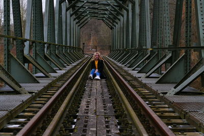 Woman sitting on railway bridge