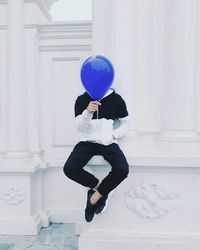 Full length of man holding balloons against wall