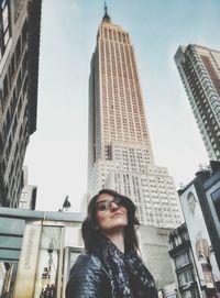 Young woman standing in front of empire state building against sky