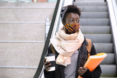 Woman holding umbrella while sitting on staircase