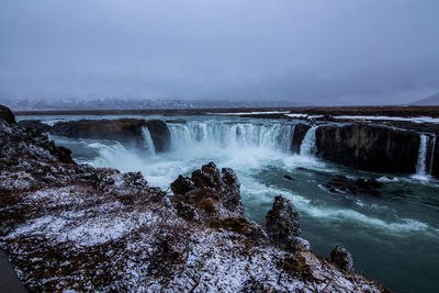 Scenic view of waterfall against sky