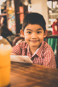 Portrait of happy boy sitting by table 