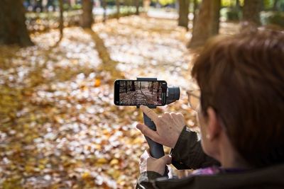 Woman photographing on mobile phone in park