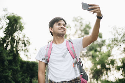 Smiling man photographing standing outdoors