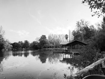 House by lake and buildings against sky
