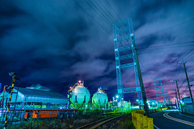 Illuminated factory against sky at night