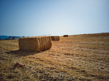 Hay bales on field against clear sky