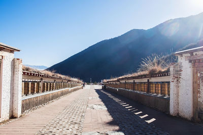 Footpath amidst buildings against blue sky