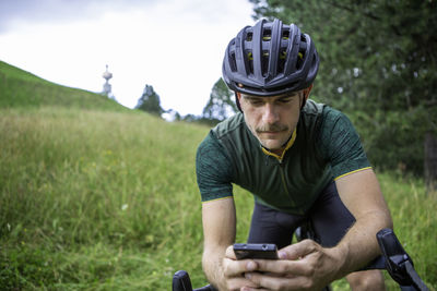 Man riding bicycle while using mobile phone outdoors