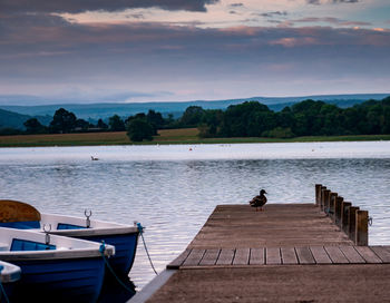 Pier over lake against sky during sunset